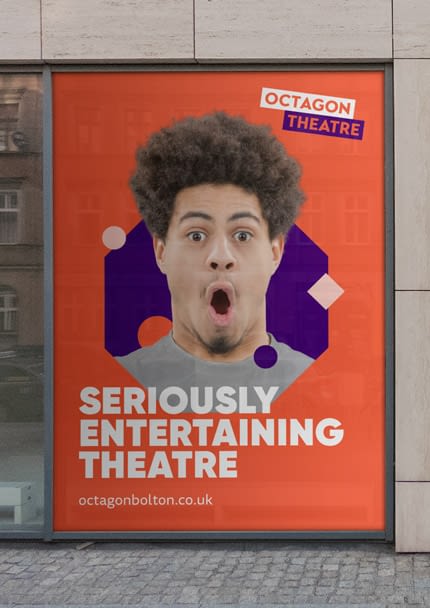 Octagon Theatre poster. An older young male youth looks excited and surprised. He is situated in a purple octagon on a orange background. The Octagon Theatre logo is in the top right. The text reads: "Seriously entertaining theatre". The web address reads: "octagonbolton.co.uk".