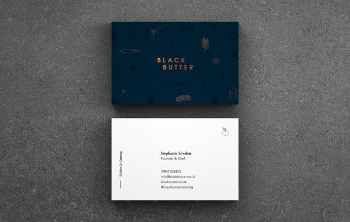 A duplex business card for Black Butter. The logo is displayed in copper foil on the front on a dark teal card stock. Brand illustrations subtly Frame the logo. The reverse displays contact information on a white card stock.