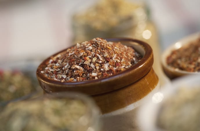 Photograph focussing in on a traditional ceramic pot containing British BBQ Rub, surrounded by jars and pots containing other Great British Butcher Rubs and Crumbs.
