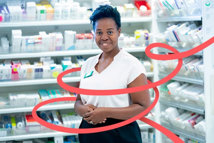 A young, black pharmacist standing in front of pharmaceutical medication - with the Pharmacist Support lines lines embracing her.