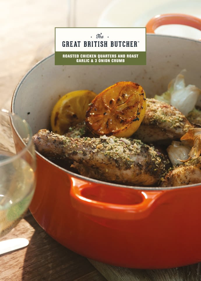 The front of a branded recipe card, presenting a wholesome pot of chicken quarters with lemons - prepared with Roast Garlic and 3 onion Crumb, next to a glass of white wine on a rustic wooden table.