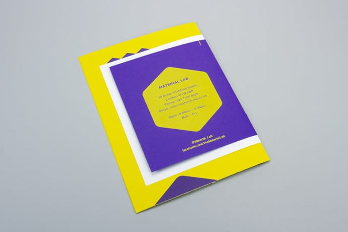 The reverse of the booklet. The back page is purple with a screen printed yellow hexagon. As the cover is smaller that the inner pages, the yellow and white inner pages can be seen poking out above, below and to the left.