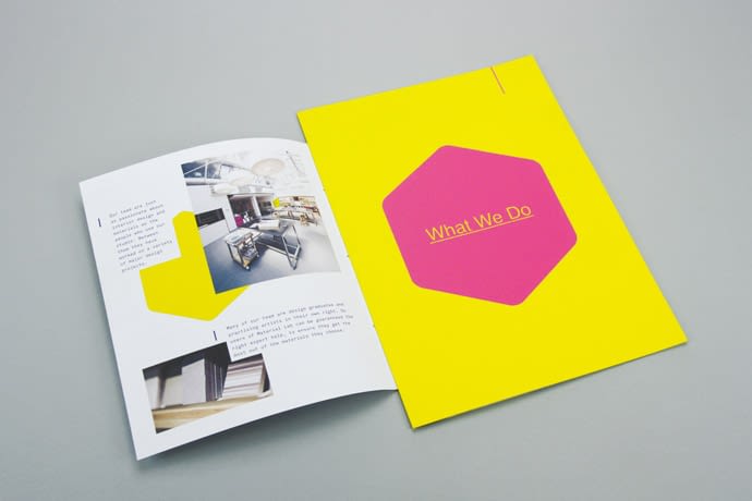 The next page is on the paper stock; Colorplan Factory Yellow Granular emboss. This page is larger than the page before. It has a magenta hexagon screen printed on it, with the words' "What we do" inverted in the centre.